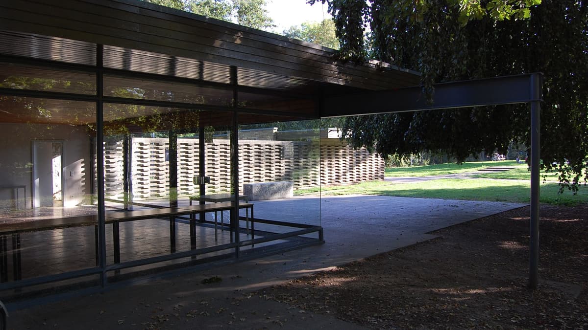 Glashaus Parkseite: Blick durch die rahmenlose verglaste Ecksituation des Hauptraumes mit „spider leg“ auf Terrasse und Mauerscheibe