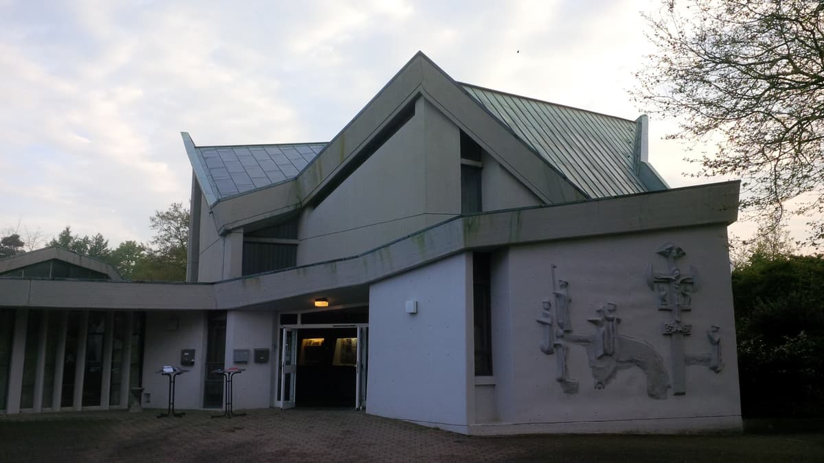 Das Relief wurde gestaltet vom Bildhauer Hermann Stehr. Es zeigt Jesus am Kreuz sowie umstehende nahestehende Personen. Auf der linken Seite begeben sich Gläubige auf einen Pilgerweg. Bei manchen von ihnen kann man den Muschelhut erkennen.