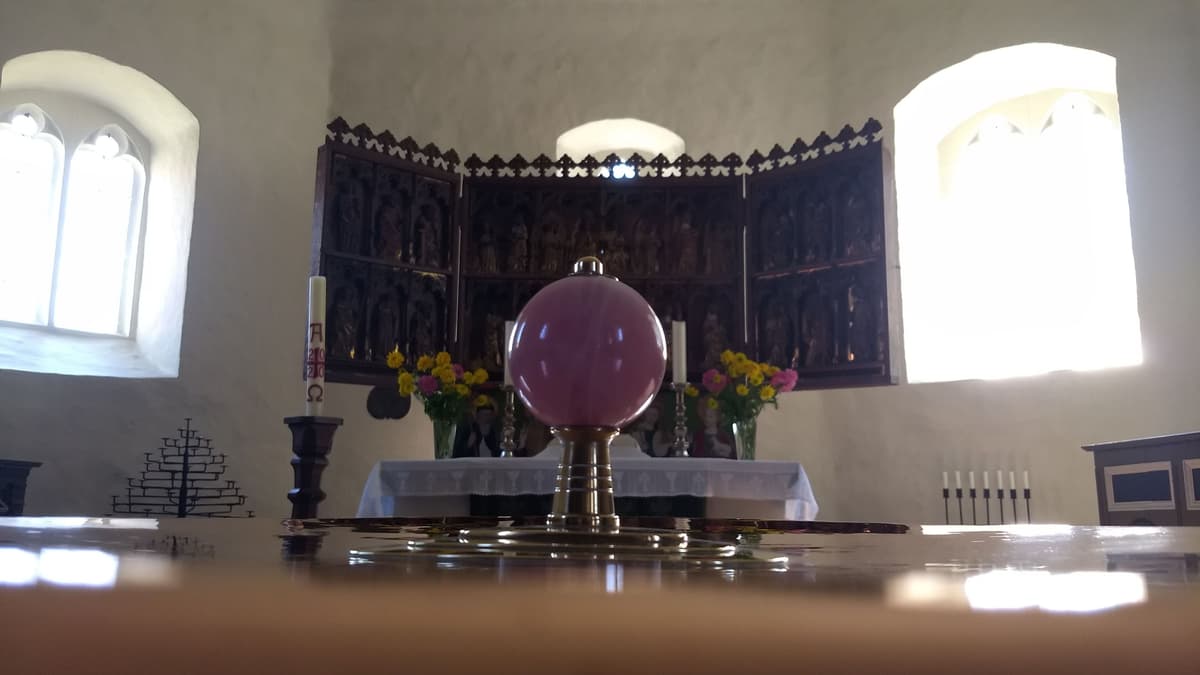 Blick über das Taufbecken auf den Flügelaltar